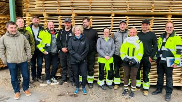 Iisveden Metsän henkilöstö hymyilee puupinon edessä työ- ja huomiovaatteissaan yhdessä LABin lehtori Markku Levasen kanssa.