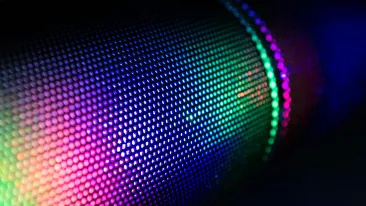 Pimeässä tilassa olevan sylinterin sisältä hohtaa valoa, joka näyttäytyy laajana väriskaalana.