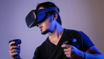 Aktiivisessa ja keskittyneessä asennossa oleva henkilö käyttää virtuaalitodellisuusteknologiaa, päässään VR-lasit ja kädessään VR-ohjaimet.