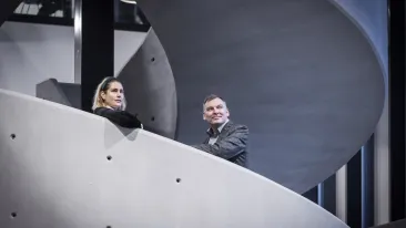 Nainen ja mies ovat pysähtyneet betonista tehtyyn kierreportaikkoon ja katsovat kaukaisuuteen.