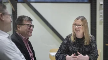 Henkilöt keskustelevat pöydän ääressä istuen.